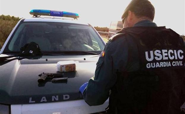 Un agente de la Guardia Civil con la pistola y el dinero incautados.