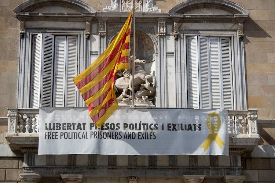 Vista de la fachada del Palau de la Generalitat de donde cuelga, junto a la bandera catalana, un cartel y un lazo amarillo reivindicando la libertad de los políticos encarcelados.