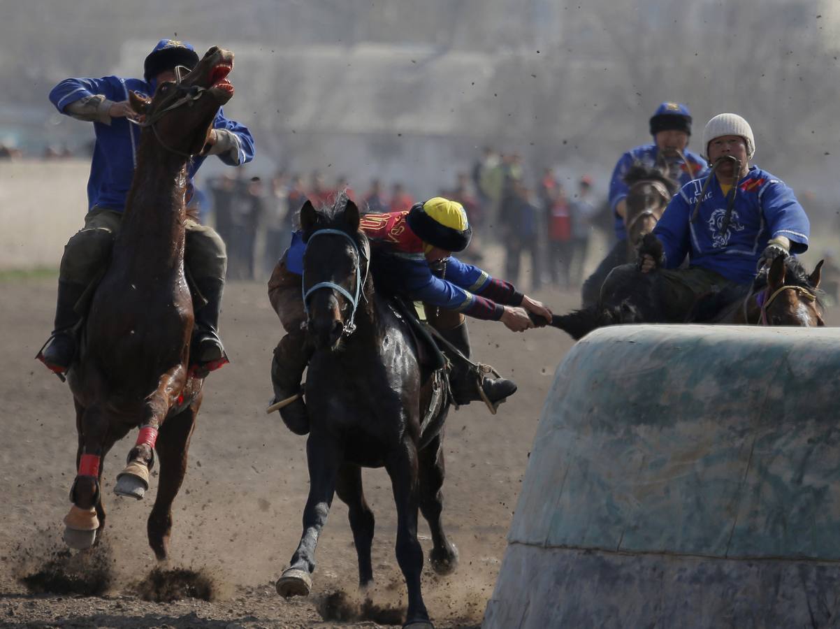 Varios jinetes participan en la competición tradicional kirguizistana llamada 'Kok-Boru', o arrastre de la cabra, con motivo de las celebraciones del Año Nuevo en el calendario solar persa, en Biskek (Kirguizistán). En el Kok-Boru los jugadores deben agarrar el cuerpo de una cabra desde el suelo mientras montan a caballo e intentar anotar un tanto al dejarlo sobre la portería del contrario.