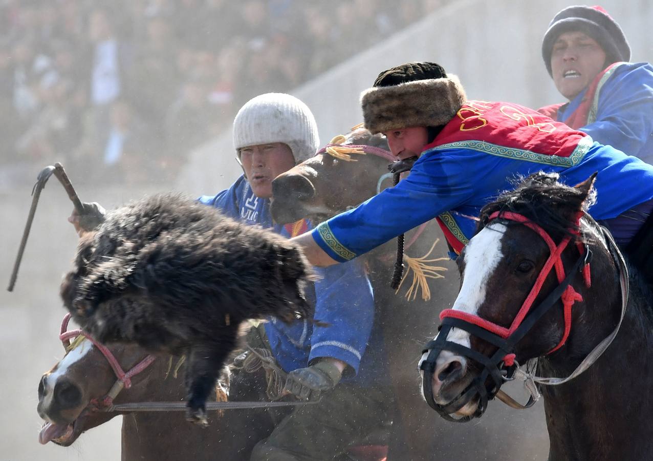 Varios jinetes participan en la competición tradicional kirguizistana llamada 'Kok-Boru', o arrastre de la cabra, con motivo de las celebraciones del Año Nuevo en el calendario solar persa, en Biskek (Kirguizistán). En el Kok-Boru los jugadores deben agarrar el cuerpo de una cabra desde el suelo mientras montan a caballo e intentar anotar un tanto al dejarlo sobre la portería del contrario.