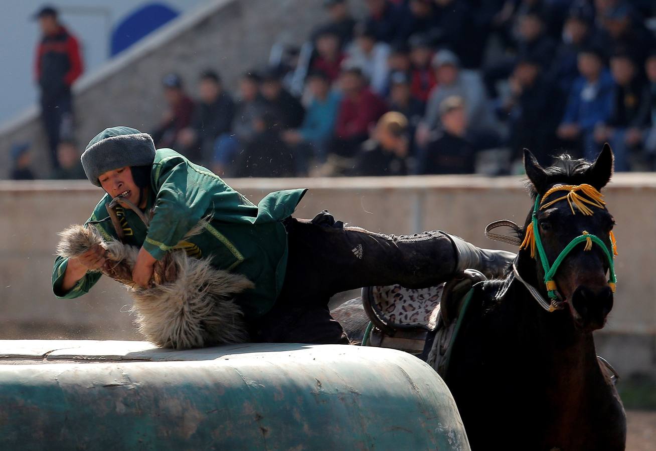 Varios jinetes participan en la competición tradicional kirguizistana llamada 'Kok-Boru', o arrastre de la cabra, con motivo de las celebraciones del Año Nuevo en el calendario solar persa, en Biskek (Kirguizistán). En el Kok-Boru los jugadores deben agarrar el cuerpo de una cabra desde el suelo mientras montan a caballo e intentar anotar un tanto al dejarlo sobre la portería del contrario.