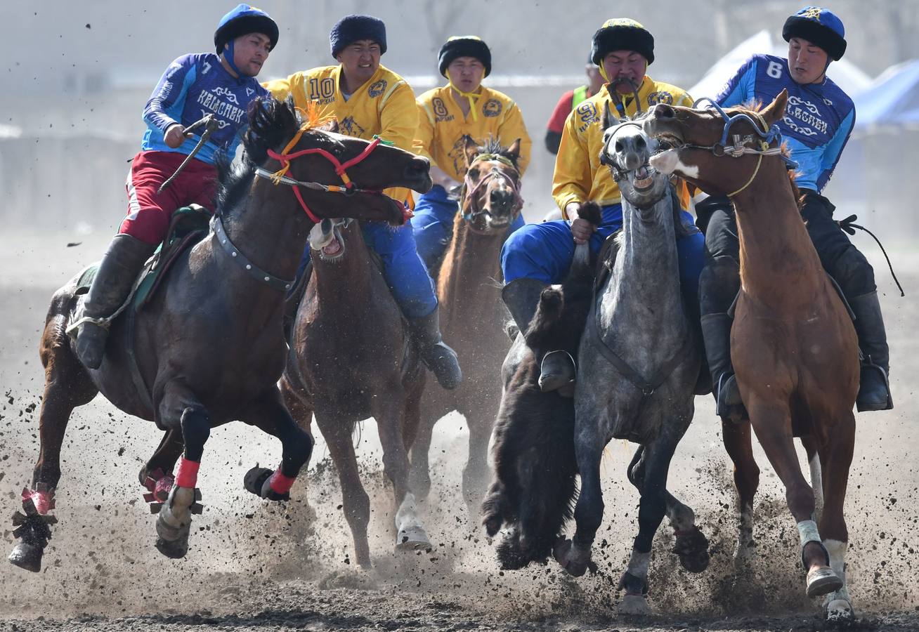 Varios jinetes participan en la competición tradicional kirguizistana llamada 'Kok-Boru', o arrastre de la cabra, con motivo de las celebraciones del Año Nuevo en el calendario solar persa, en Biskek (Kirguizistán). En el Kok-Boru los jugadores deben agarrar el cuerpo de una cabra desde el suelo mientras montan a caballo e intentar anotar un tanto al dejarlo sobre la portería del contrario.