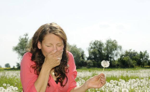 Una mujer estornuda en un lugar con mucho polen 