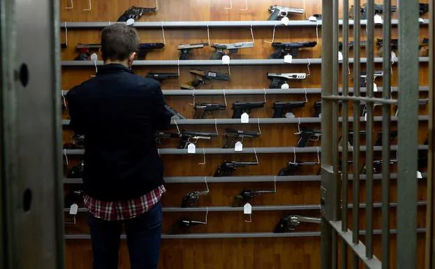 Un cliente examina las pistolas y revólveres expuestos en la Armería del Carmen.