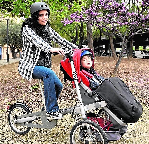 Lorena Laos posa con su hijo Víctor y su controvertido triciclo en un jardín de Murcia. 