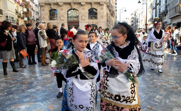 Dos niñas, vestidas con el traje típico y con sus ramos de flores en las manos, camino de la basílica, durante la ofrenda a la Patrona.