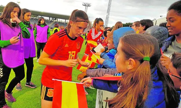 Eva firma autógrafos, ayer al final, en una imagen cedida por su familia; a la derecha, durante el partido. 