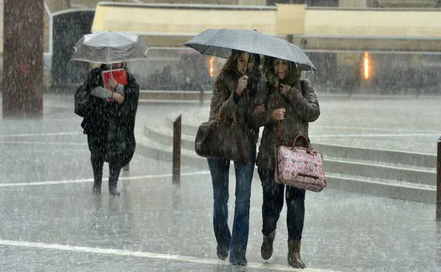 Tres mujeres pasean por Murcia en un día de intensa lluvia.