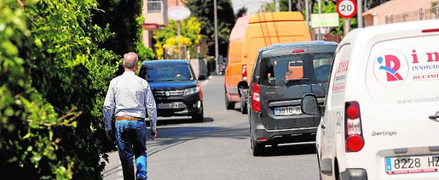 Coches circulan por la carretera de la Senda Granada a escasos metros de los peatones que recorren la vía por la ausencia de una acera en el entorno.