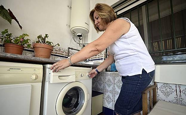Una mujer enciende la lavadora de su casa 