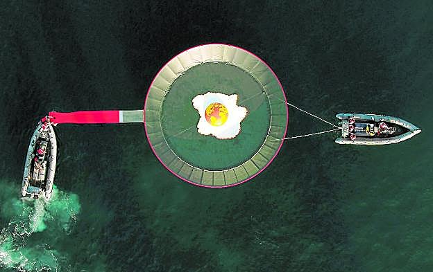 Los activistas de Greenpeace colocan la sartén con el huevo frito, ayer, en La Manga del Mar Menor. 