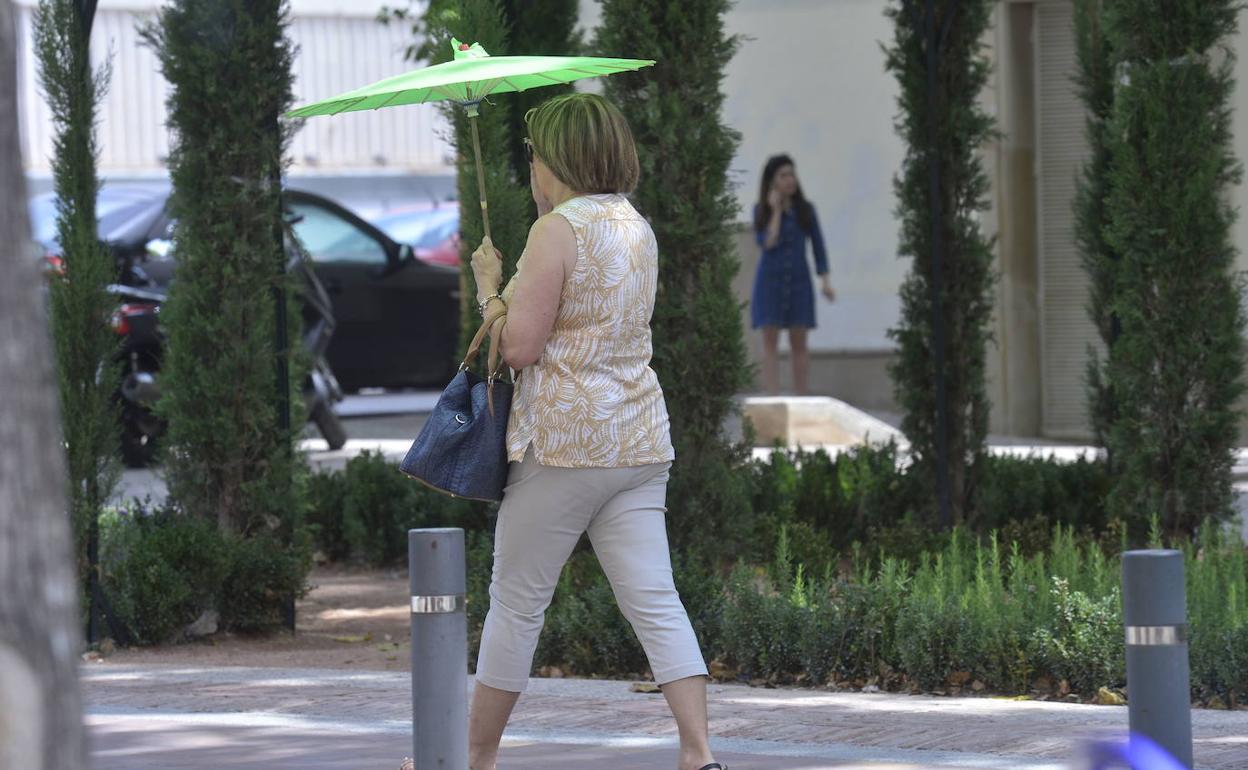 Una mujer se protege del calor con un paraguas, este verano, en Murcia.