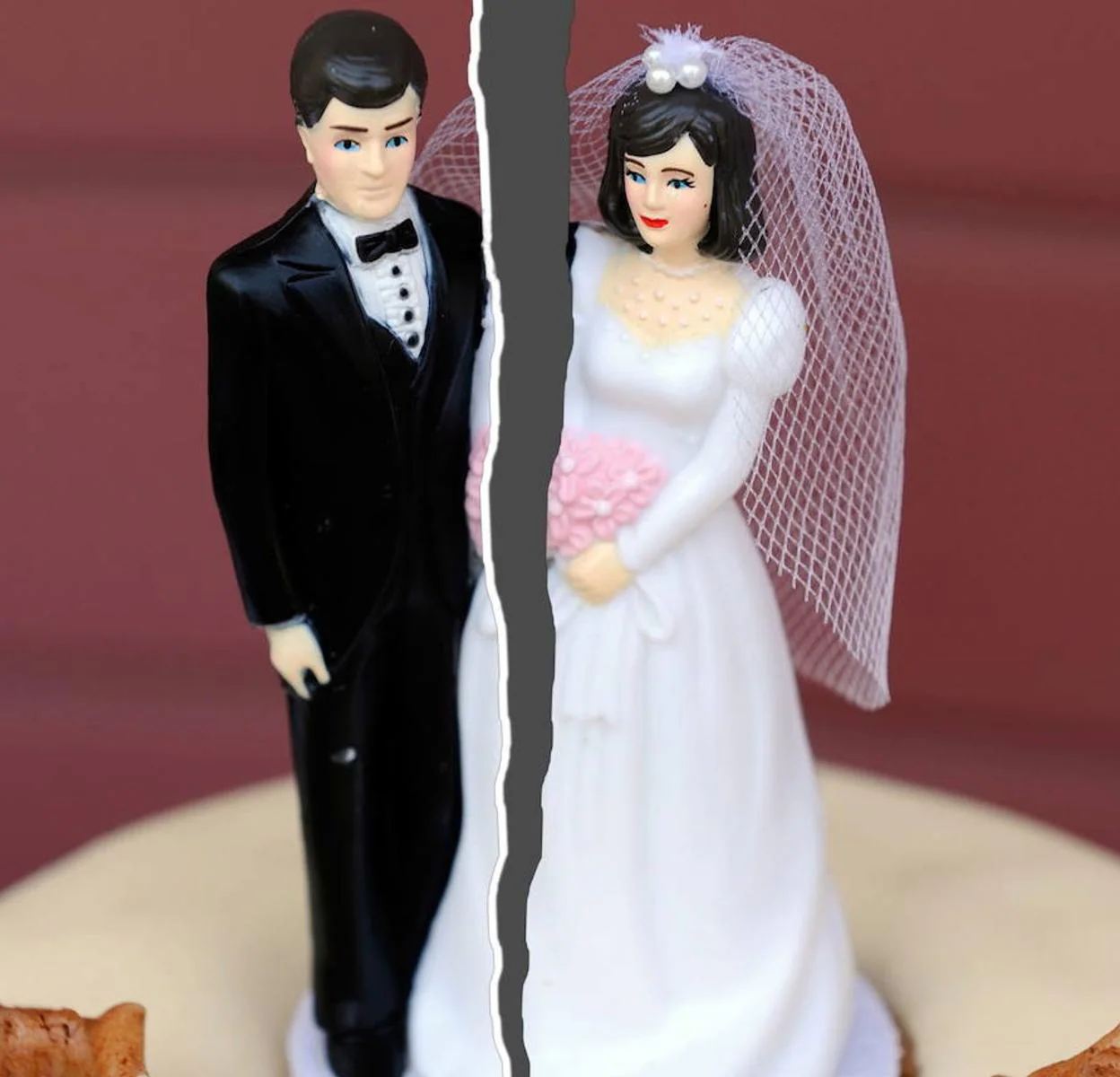Imagen de muñecos en una tarta de boda rota por la mitad.