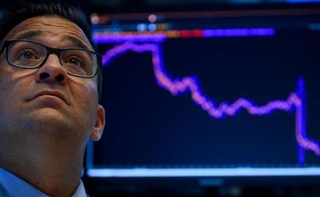 Un trader estadounidense ante un chart con la caída de la Bolsa el lunes.
