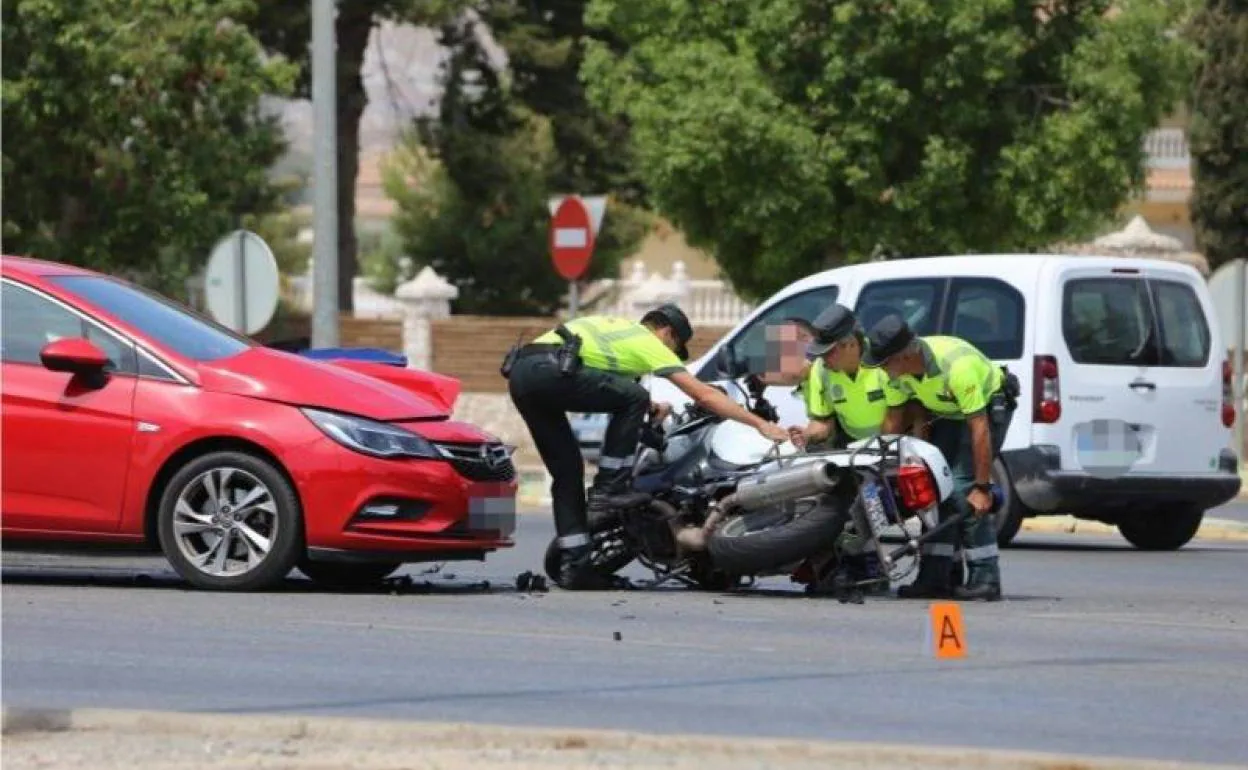 Varios agentes de la Guardia Civil levantan la motocicleta tras la colisión con el vehículo.