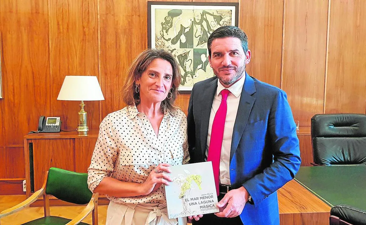 La ministra en funciones Teresa Ribera y el consejero Luengo sostienen un libro sobre el Mar Menor.