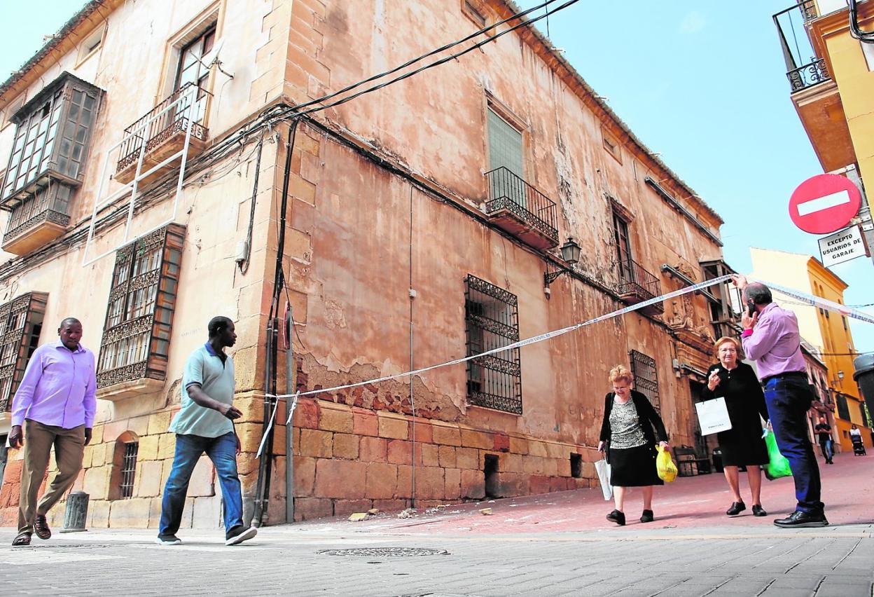 Un hombre ayuda a dos vecinas a pasar bajo el cordón de seguridad que impide transitar junto a la casa de Los Guevara 