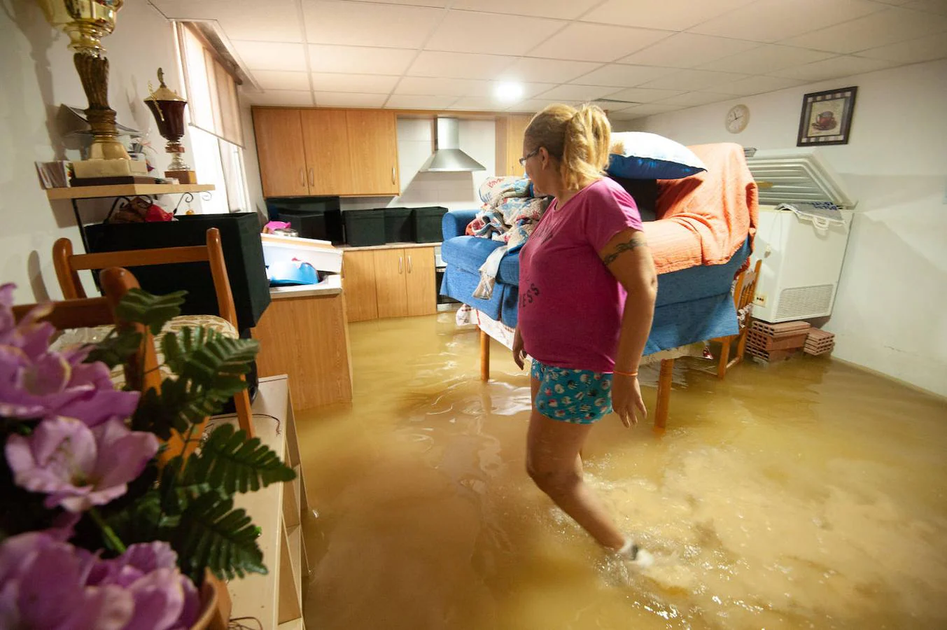 Una vecina de la pedanía murciana de Alquerías intenta sacar el agua de su casa inundada.