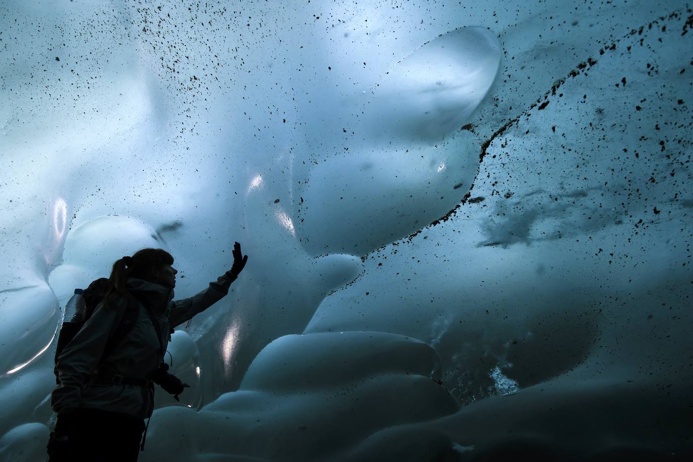 Un hombre mira el glaciar Aletsch desde una cavidad interior, en el Cantón de Valais (Suiza). El glaciar suizo Aletsch es uno más grandes de Europa y el primer lugar de los Alpes declarado Patrimonio de la Humanidad por la Unesco. Este enorme río de hielo se extiende a lo largo de 23 km desde su formación en la región de Jungfrau hasta el desfiladero de Massa, en el Cantón del Valais.
