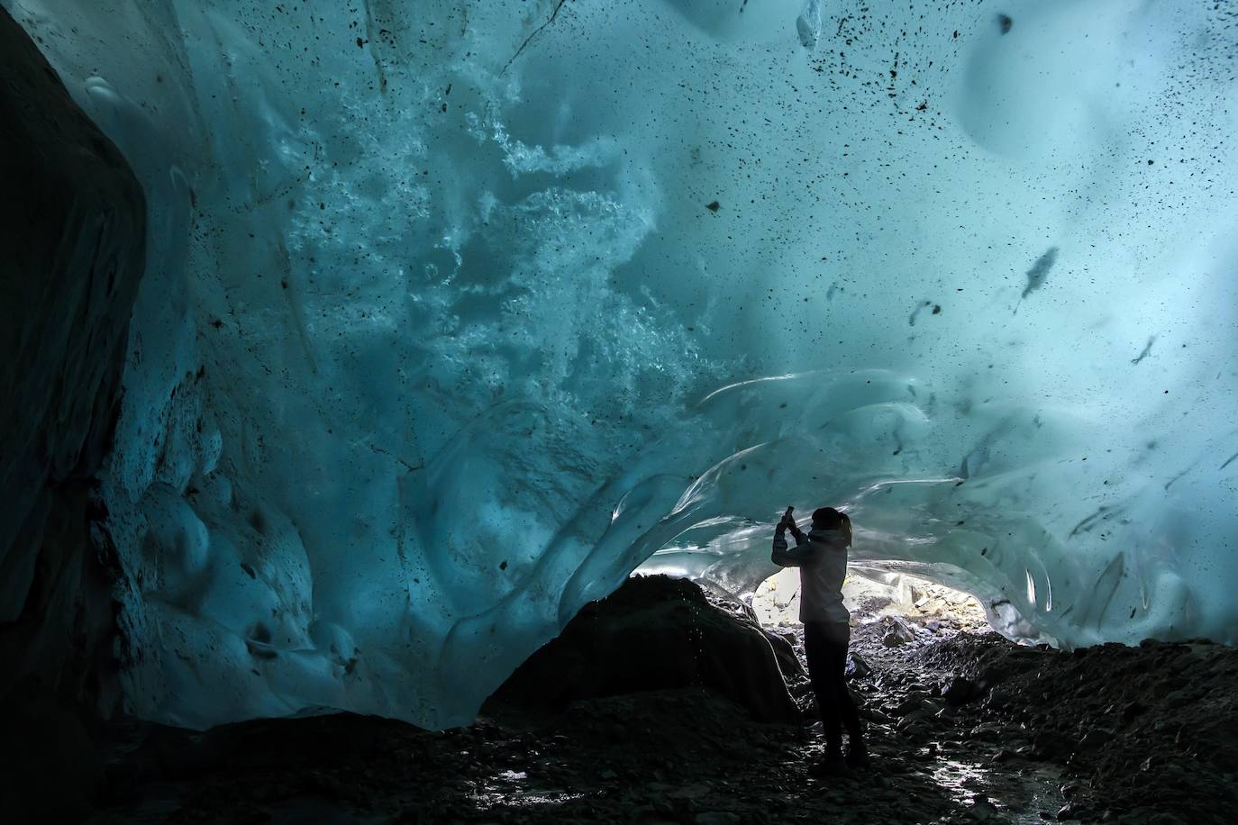 Un hombre mira el glaciar Aletsch desde una cavidad interior, en el Cantón de Valais (Suiza). El glaciar suizo Aletsch es uno más grandes de Europa y el primer lugar de los Alpes declarado Patrimonio de la Humanidad por la Unesco. Este enorme río de hielo se extiende a lo largo de 23 km desde su formación en la región de Jungfrau hasta el desfiladero de Massa, en el Cantón del Valais.