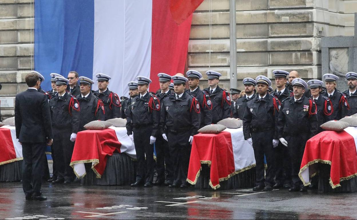 El presidente francés Emmanuel Macron frente a los féretros de las víctimas del ataque en la sede de la Perfectura en París.