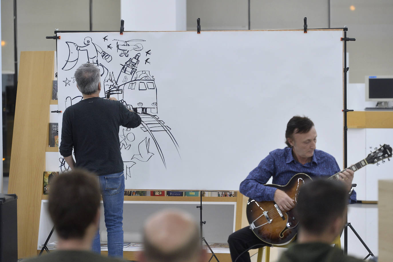 Con motivo del Día de las Bibliotecas, la Biblioteca Regional fue ayer escenario de una sesión de 'CómicJazz': espectáculo visual y sonoro en el que participaron el guitarrista Maxi Garcés y el dibujante Juan Álvarez. Garcés, que proviene del mundo del rock, interpretó piezas de jazz, pop-rock y clásicas y Álvarez dibujó en un panel de dos metros, de tal forma que los trazos aparecían al son de la música.
