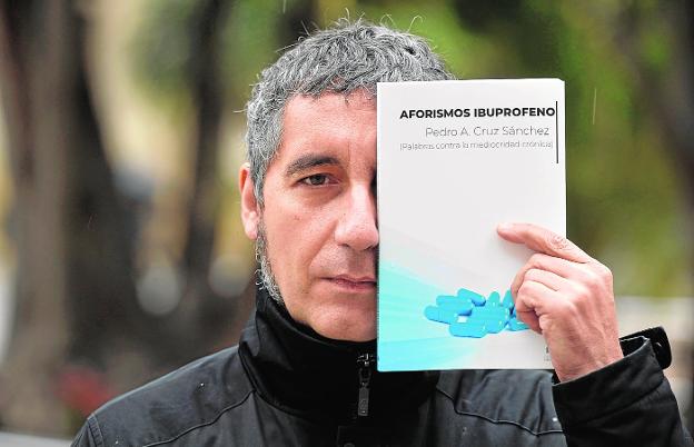 Pedro Alberto Cruz oculta la mitad de su rostro con el libro de aforismos que presenta hoy en Murcia. 