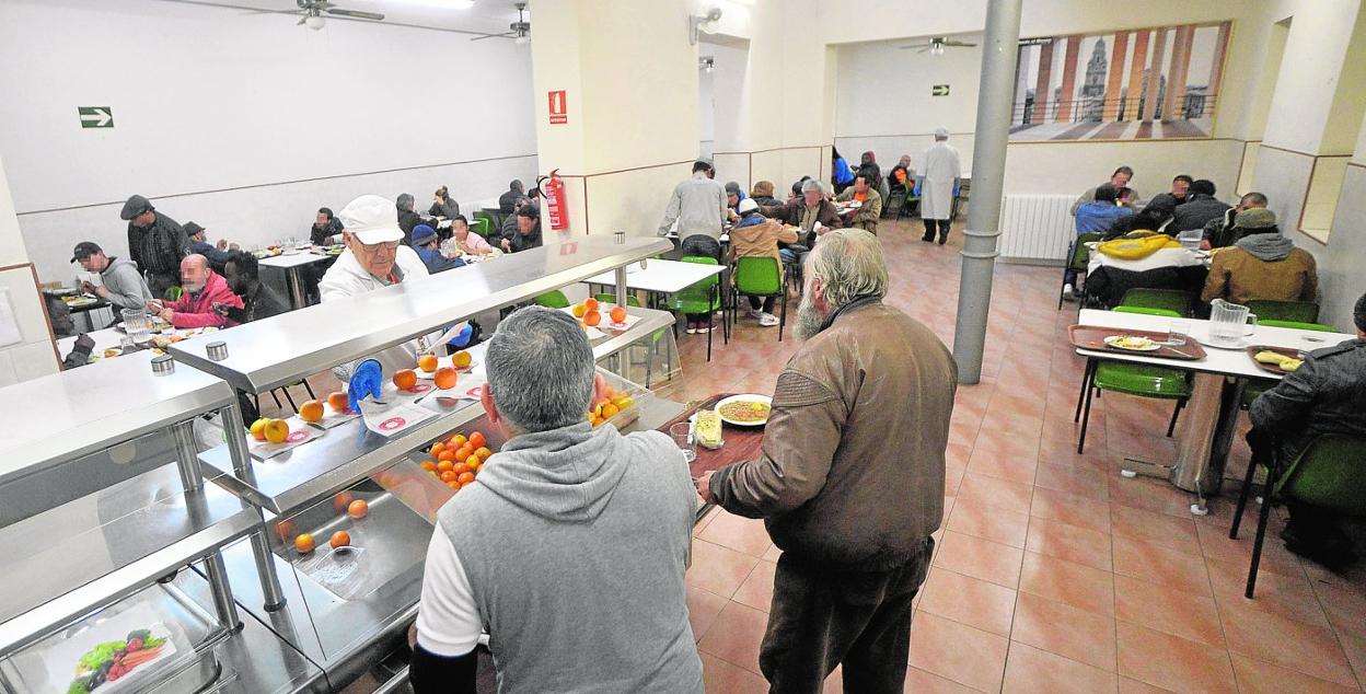 Dos usuarios de la Fundación Jesús Abandonado retiran su bandeja en el comedor social de la entidad. 
