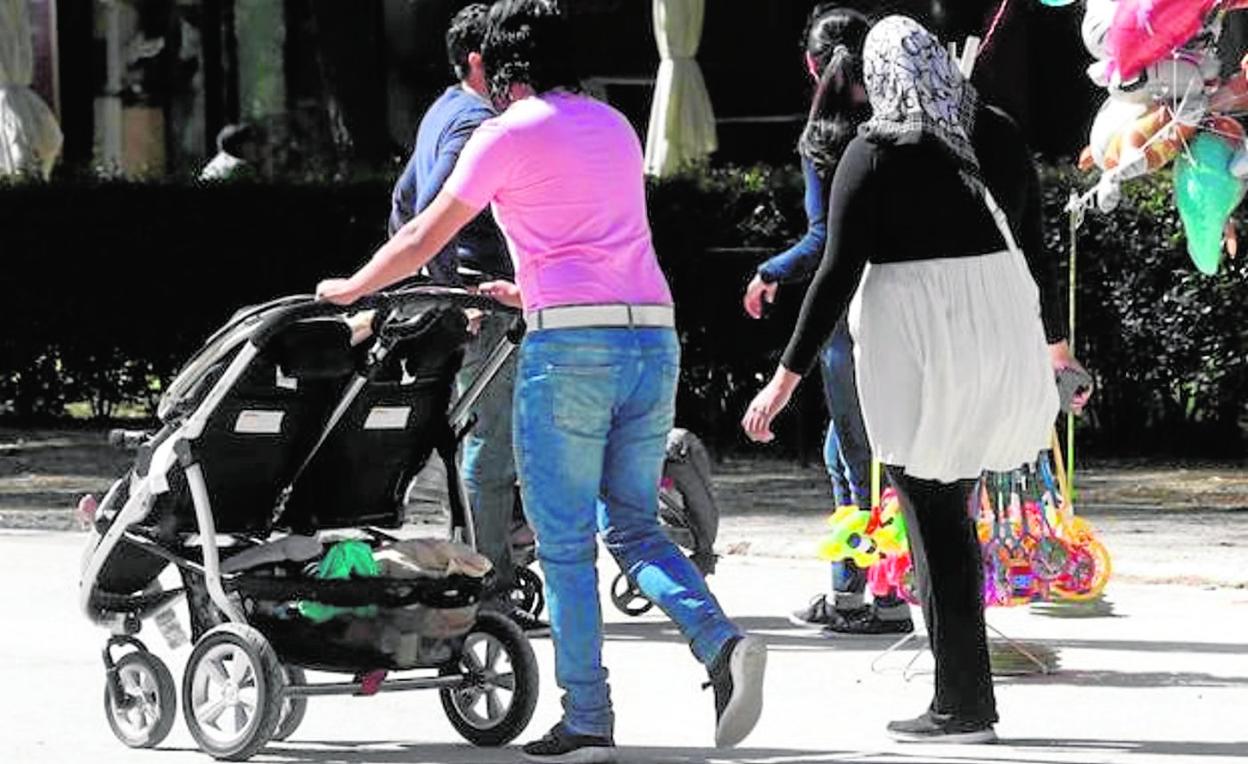 Una madre pasea con un carrito doble por una calle de la capital murciana. 