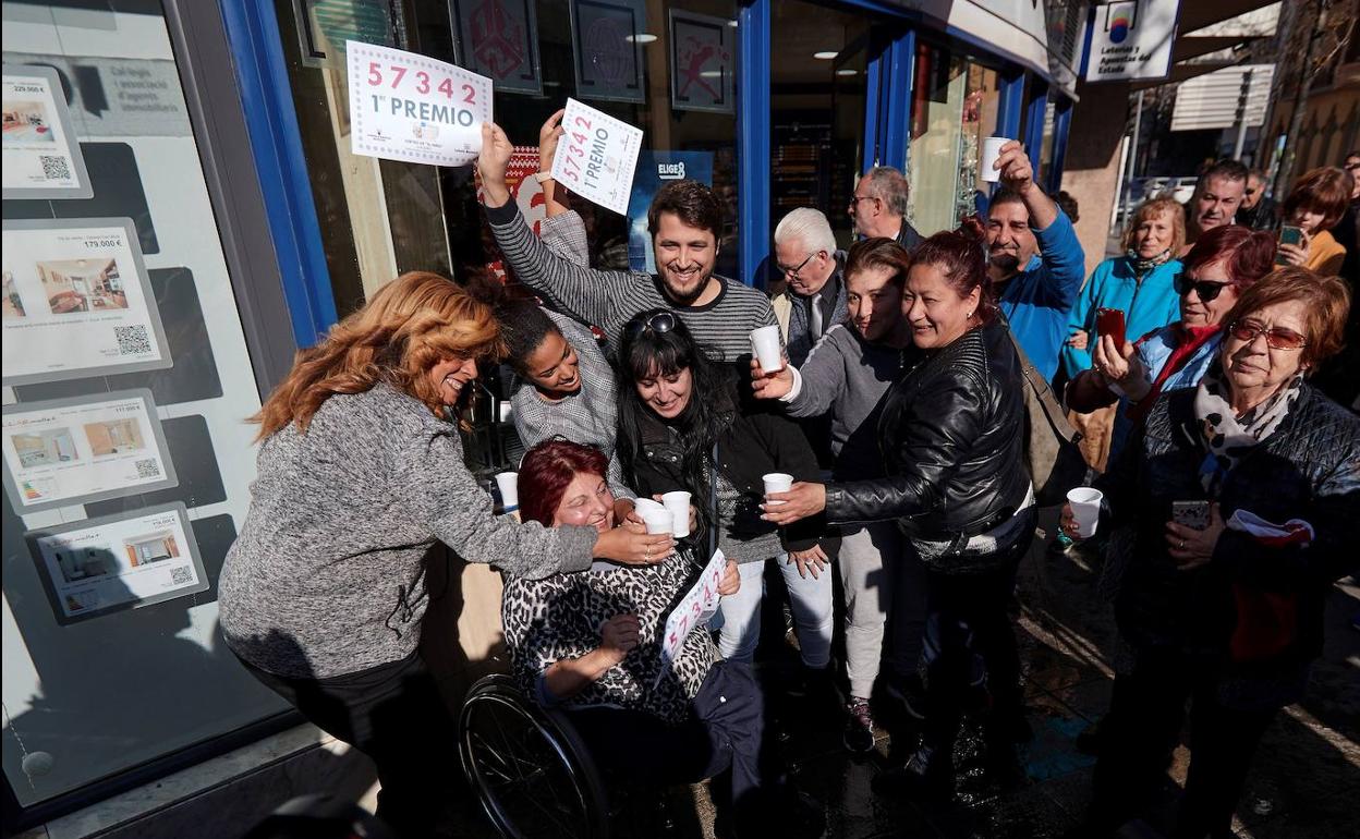 Varias personas festejan el primer premio del Sorteo extraordinario de El Niño, en la puerta de la administración de lotería de Mollet del Vallés.