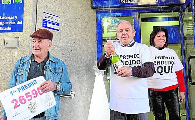 El lotero José Turpín descorcha una botella de sidra en la entrada de la administración de Beniaján, junto a José Hernández, uno de los agraciados con el Gordo.