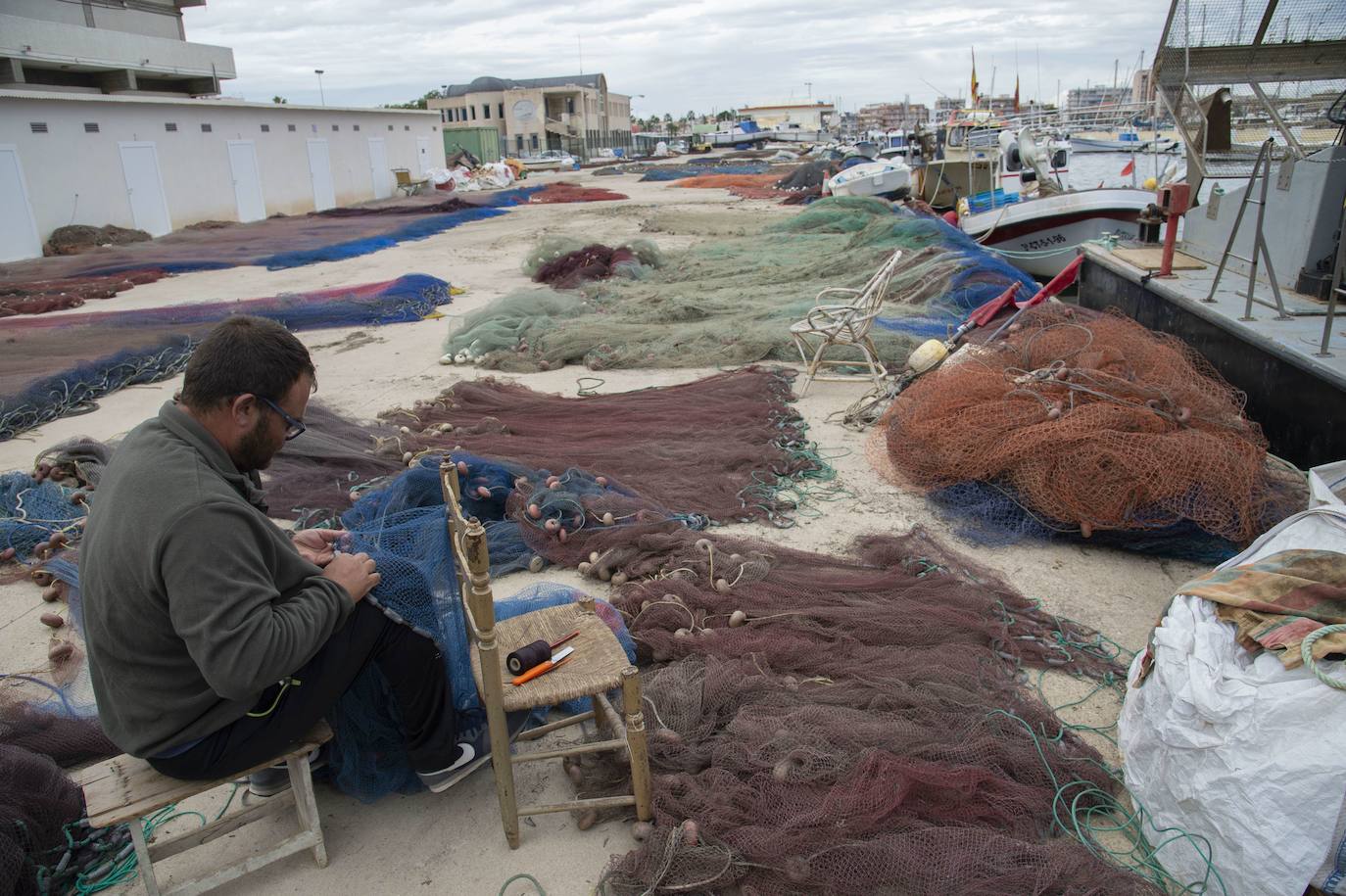 20-10-2019. Parón de pesca con la lonja a cero. Los pescadores que faenan en el Mar Menor inician un parón sin pescado que vender en la lonja de Lo Pagán. Los afectados, que reclaman ayudas, confían en recuperar la actividad en primavera. En la imagen, un pescador en el puerto de Lo Pagán remienda sus redes. :: Antonio Gil / AGM