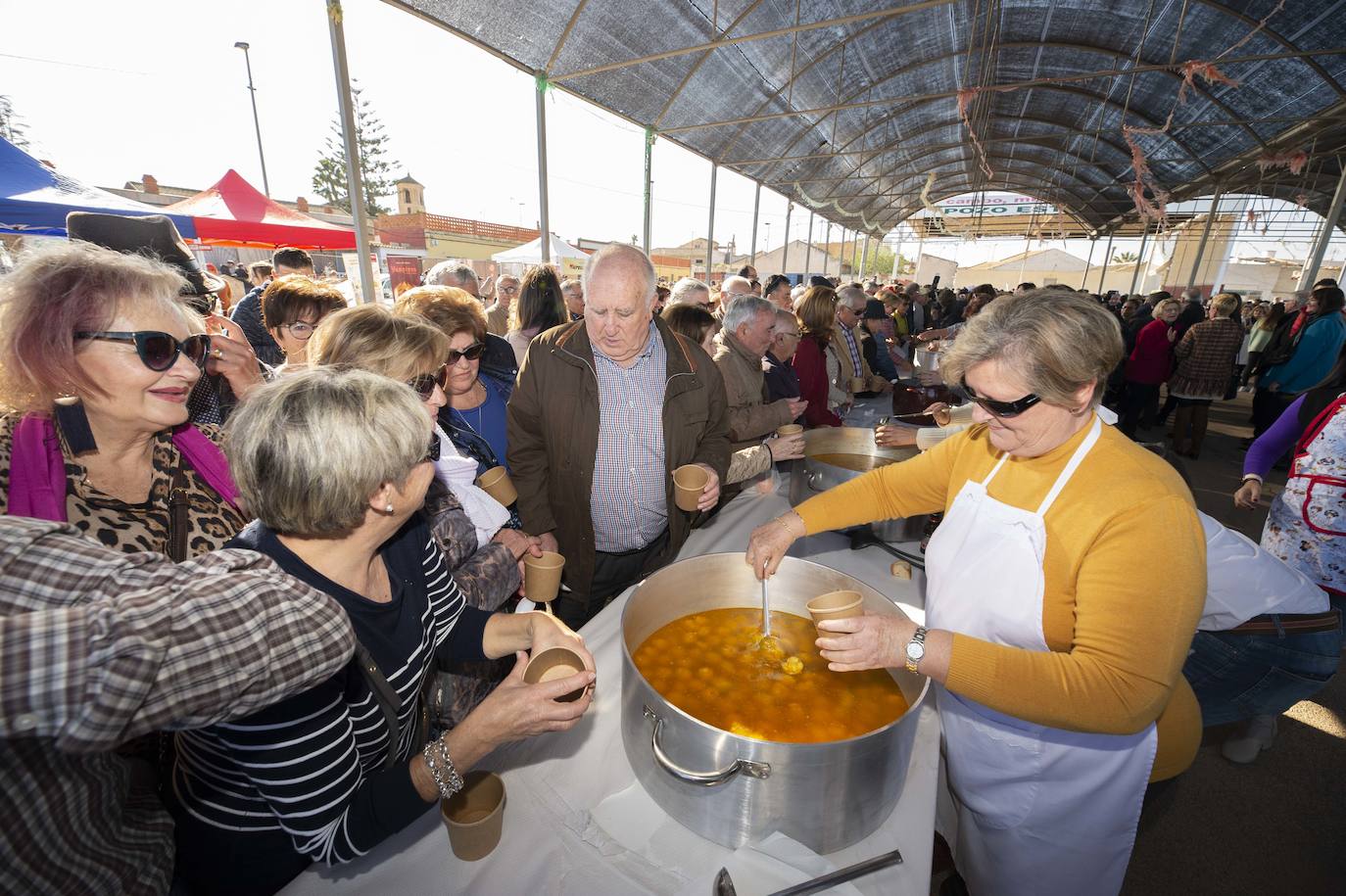 Decenas de personas se agolpan junto a las barras, donde amas de casa y peñistas sirven las típicas pelotas galileas