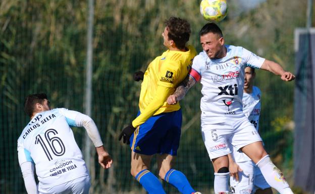 Chino, capitán del Yeclano, pelea con un delantero del Cádiz B por un balón aéreo ante la mirada de Selfa.