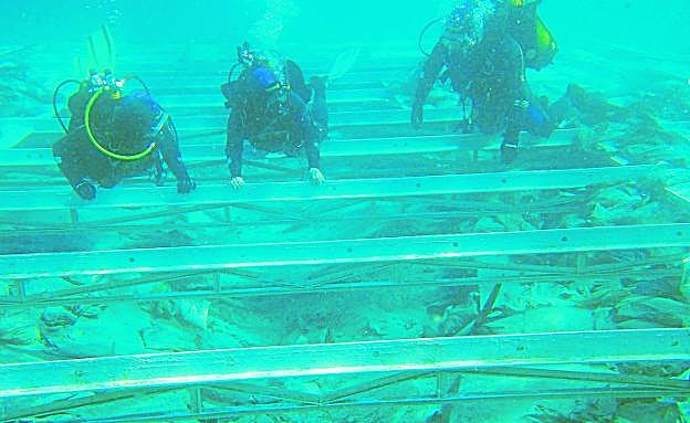 Tres arqueólogos durante una de las revisiones a la caja del pecio de La Isla, en una imagen de archivo. 