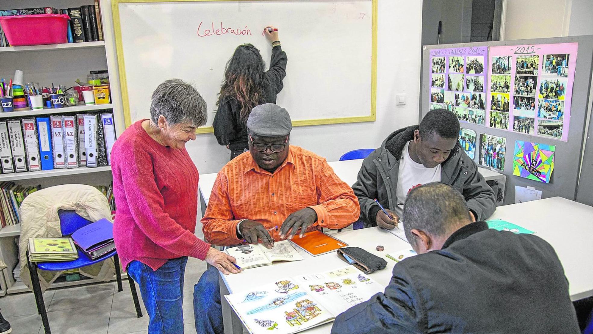 La voluntaria Isabel León enseña español a usuarios del centro de día de Accem ubicado en la barriada Virgen de la Caridad de Cartagena. 