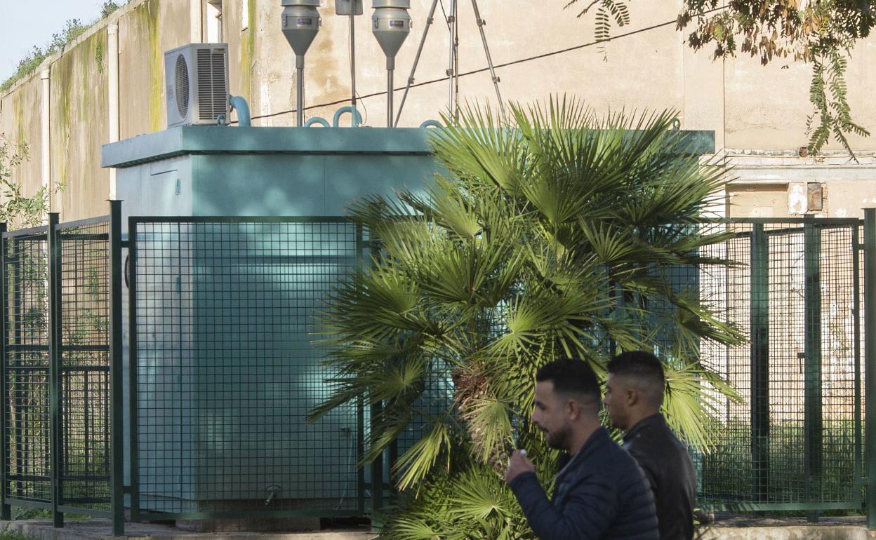 Dos hombres pasan ante la estación medidora de Mompeán. 
