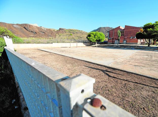 Vista de uno de los patios del colegio Enrique Viviente de La Unión, con la montaña de residuos junto a la valla, a la izquierda. 