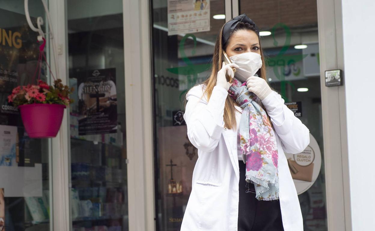 Una mujer se protege con una mascarilla en la puerta de una farmacia, en una imagen de archivo.