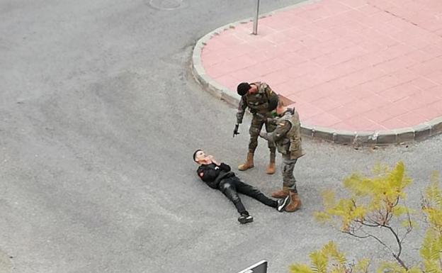 Dos soldados arrestan a un joven en el barrio de Los Rosales de El Palmar.