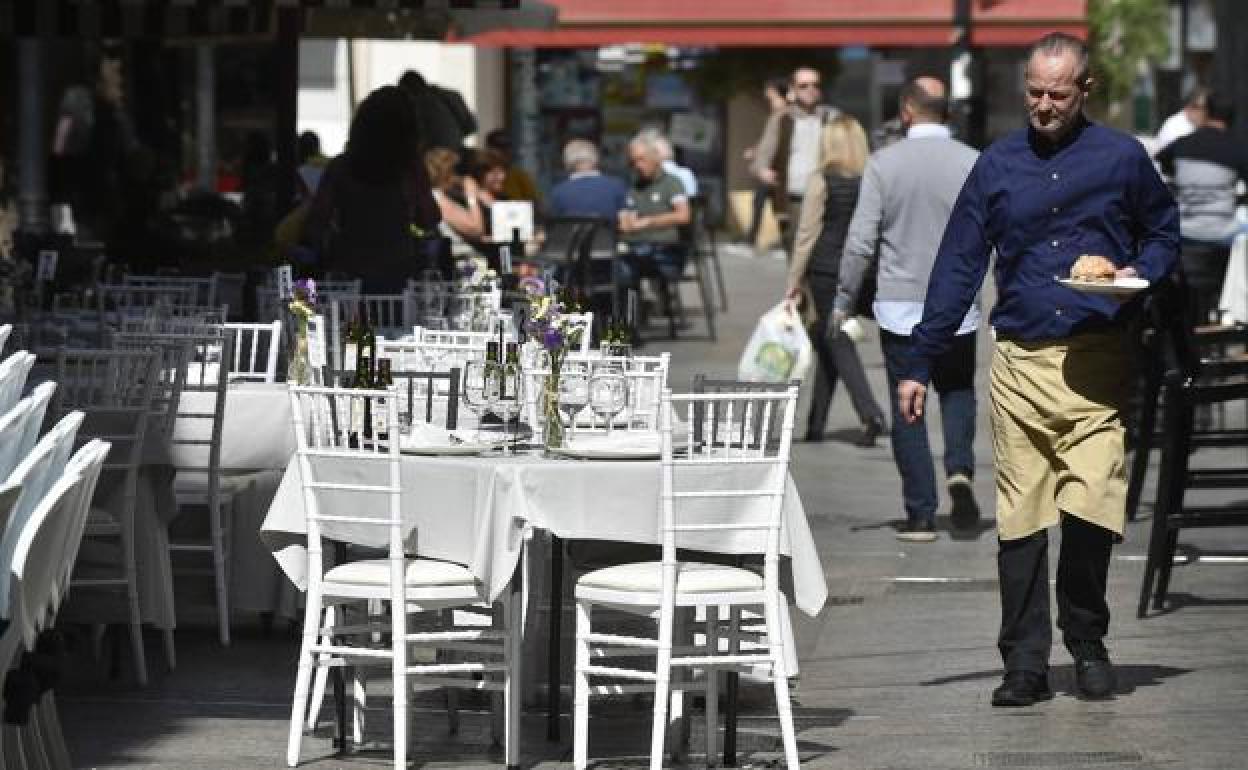 Un camarero, frente a la terraza de un bar vacía, un día antes del obligado cierre de restaurantes por el corornavirus.