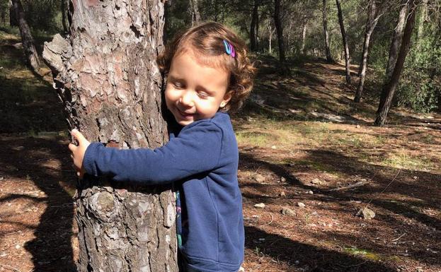 La pequeña abraza un árbol en su primera salida.