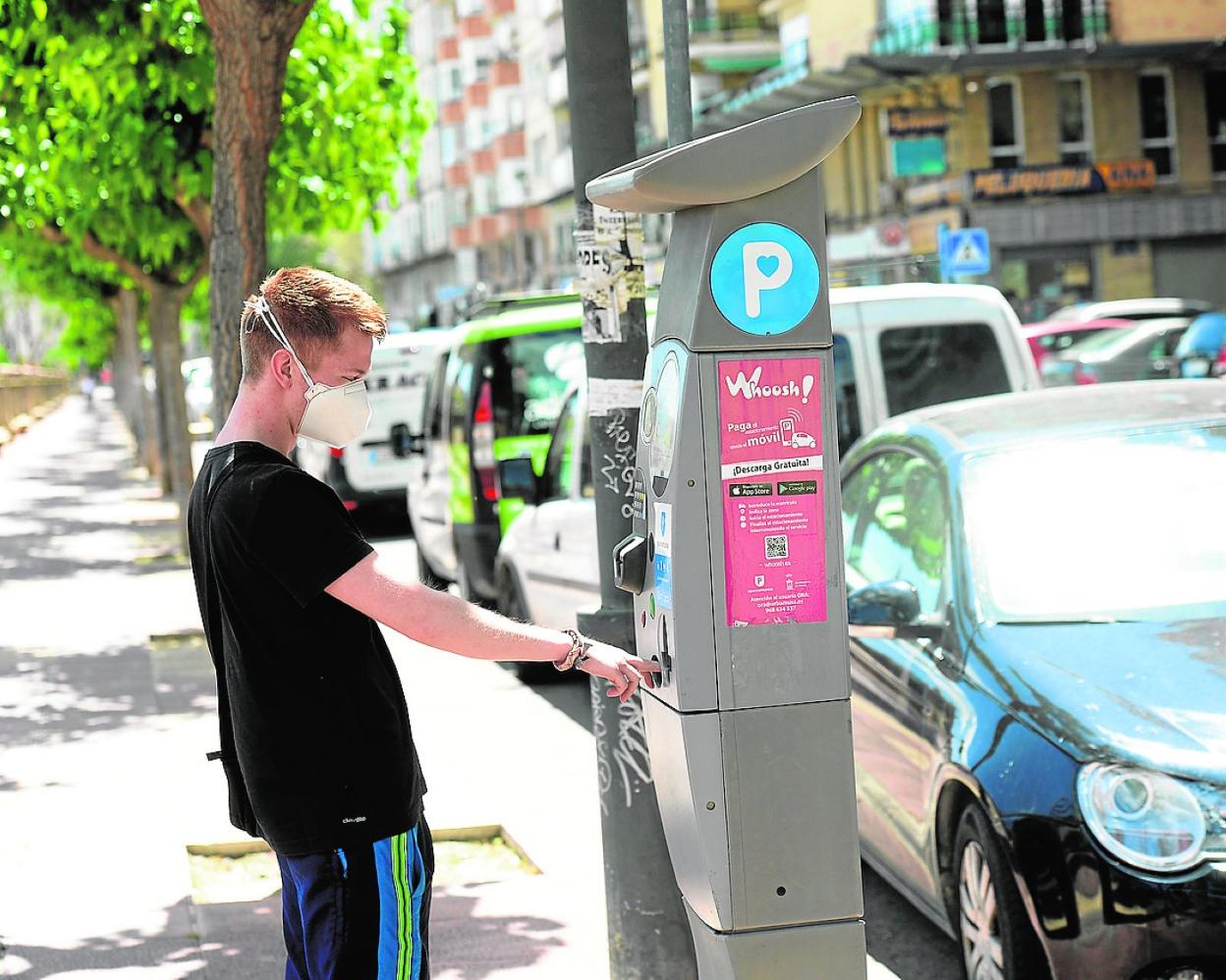 Un joven introduce monedas en un parquímetro para obtener su correspondiente tique. 