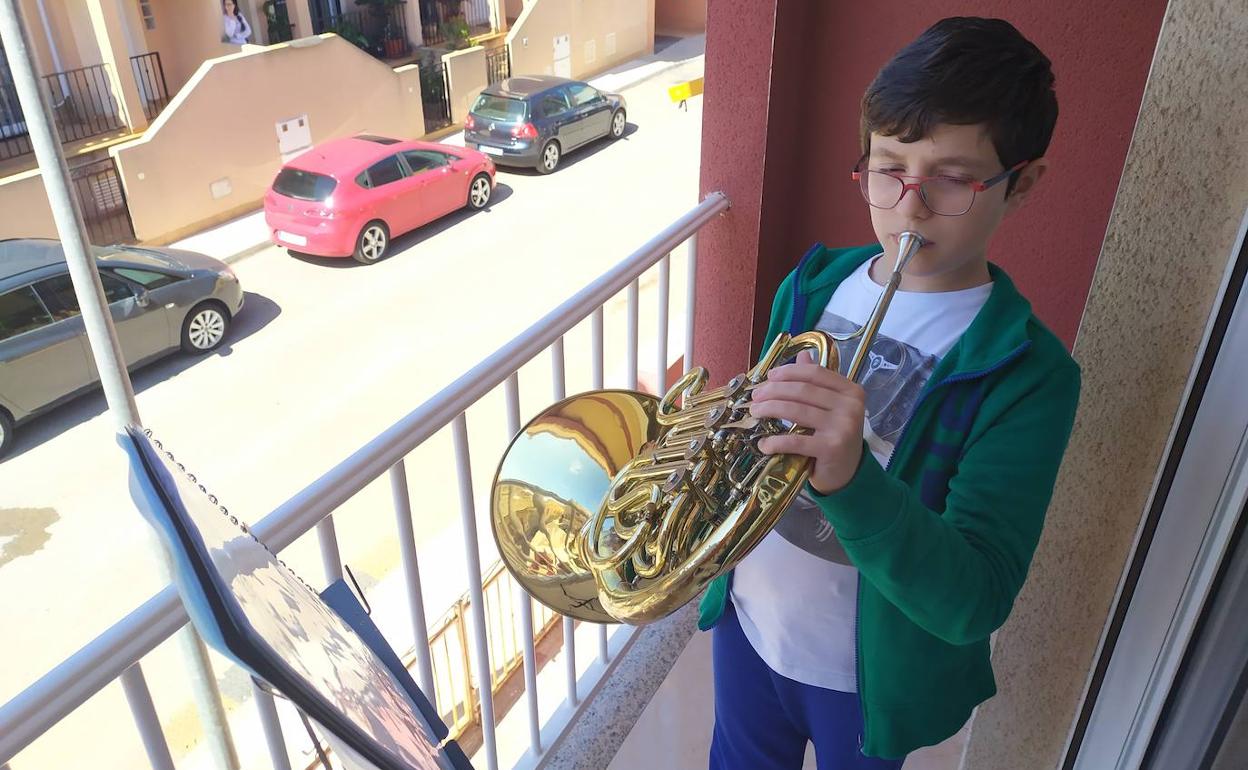 José David Rosique, en su balcón, tocando la trompa.