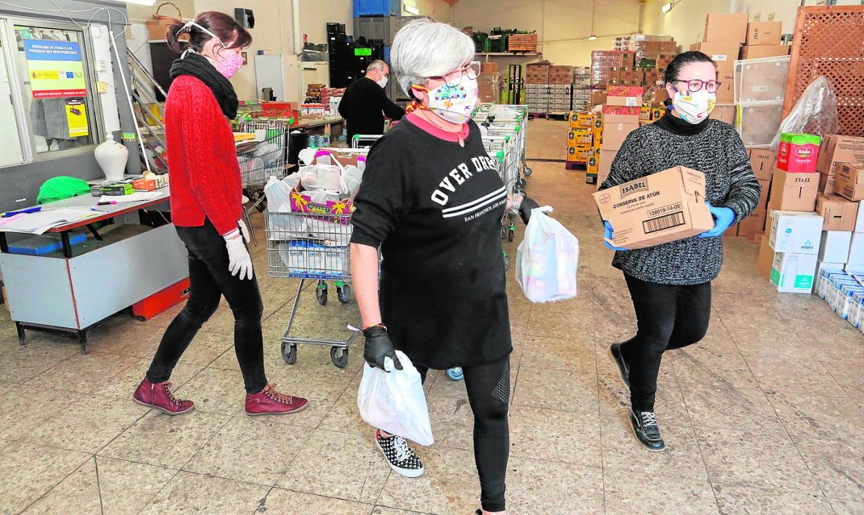 Voluntarios y personal de Cáritas durante la entrega de los carros en el banco de alimentos de la ONG. 