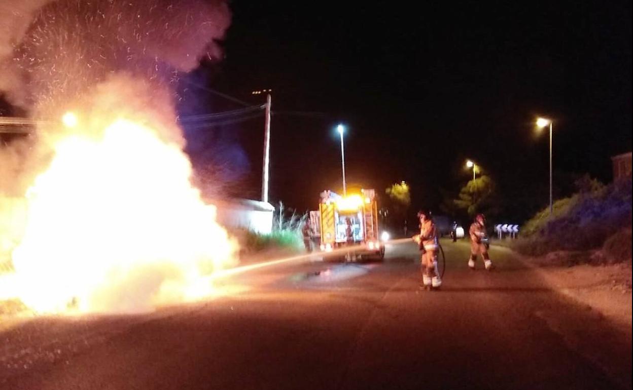 Bomberos apagando el fuego en el coche accidentado.