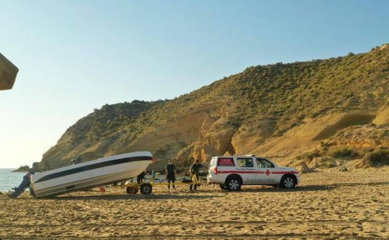 Dos agentes remolcan en Águilas la patera en la que llegó el inmigrante contagiado. 