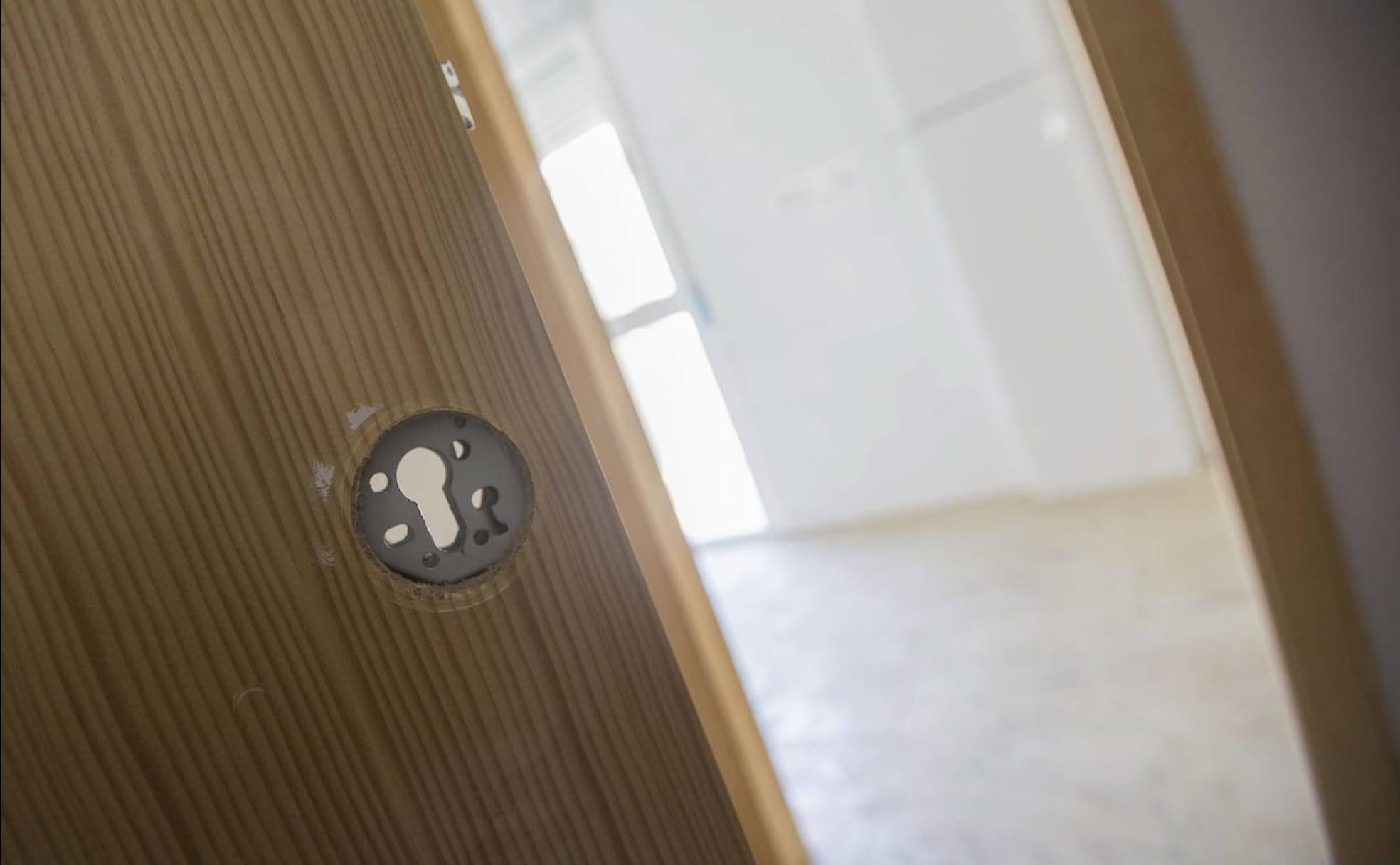 Puerta reventada en un bloque de viviendas ocupadas en Cartagena.