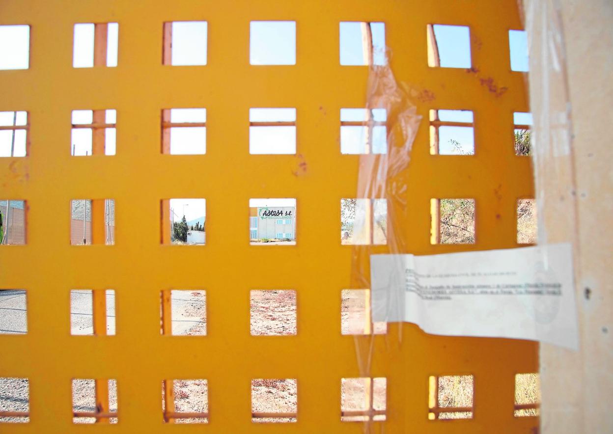 Puerta principal del recinto de la empresa, con el precinto que anuncia la prohibición judicial de que haya actividad. 