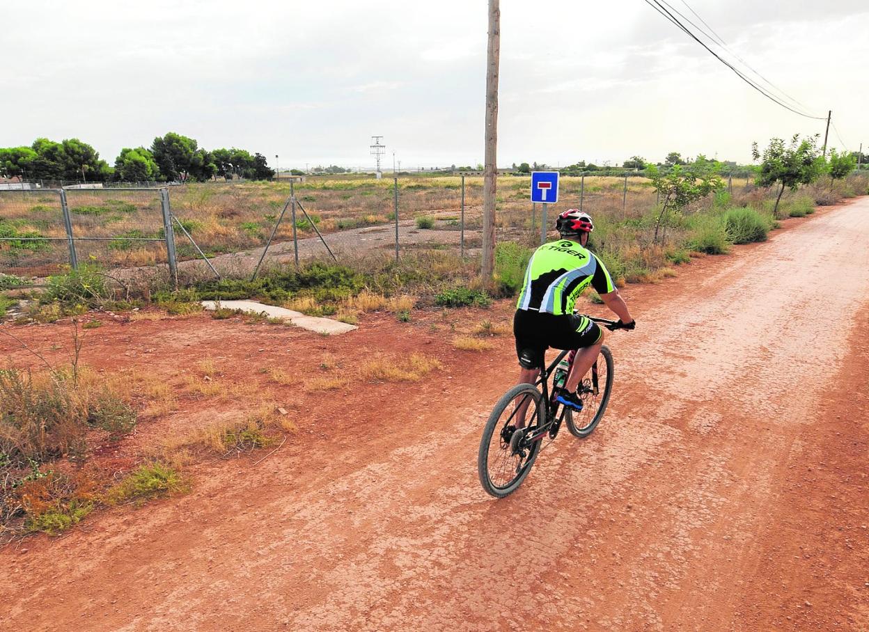 Un ciclista circula por la vía verde entre Cartagena y Totana, a su paso por La Aljorra, junto a los terrenos del nuevo colegio. 
